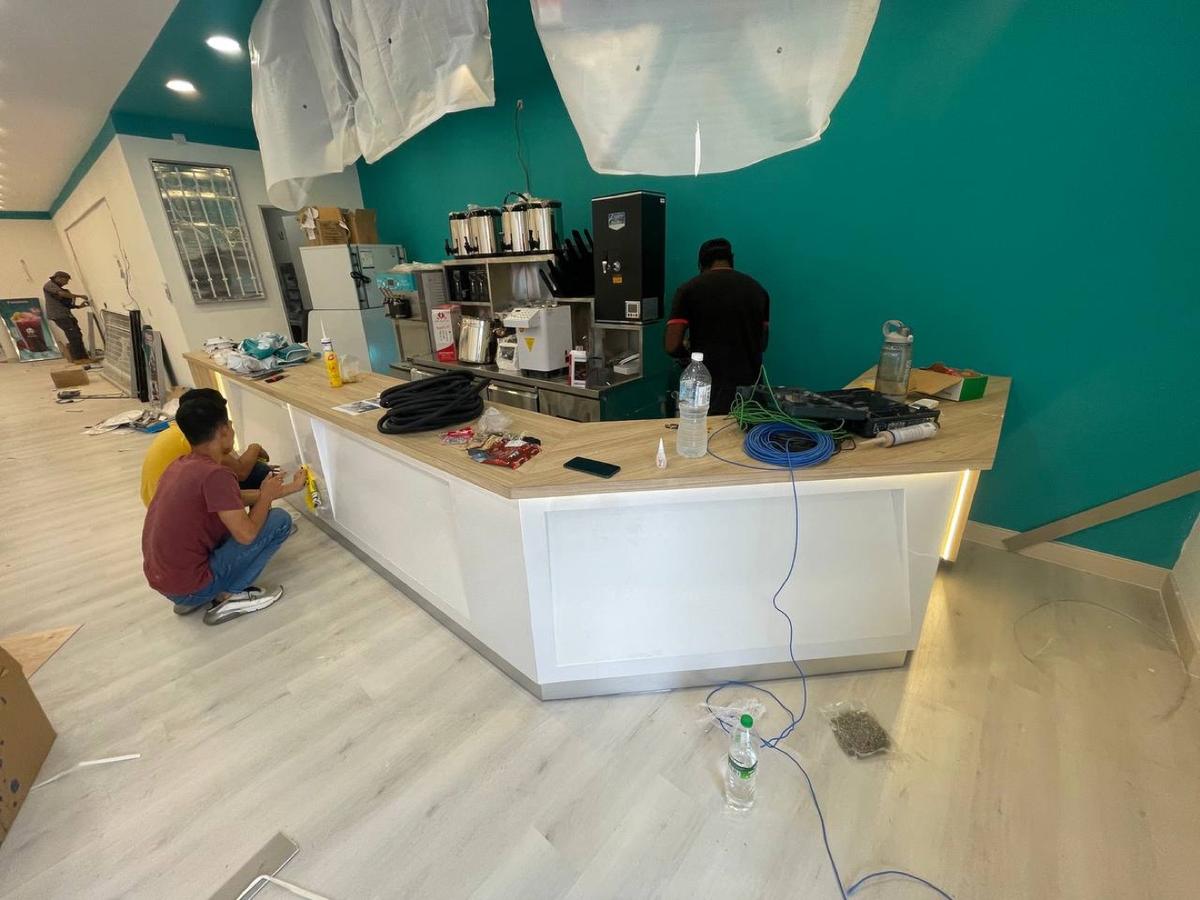 Our fitter installing a café counter against a teal wall